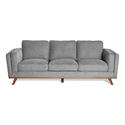 The Maddox Sofa exudes mid-century modern style with its sleek wooden legs and plush gray cushions. Its minimalist design against a white background provides both elegance and comfort.