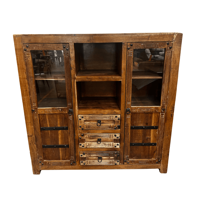 The Rustic Media Armoire features a rich, dark-finished wood with visible grain, two glass-paneled doors on each side, four central drawers, and two open shelves above. Metal accents enhance its vintage appeal.