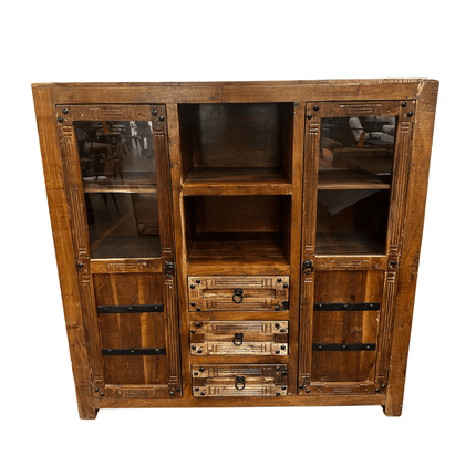 The Rustic Media Armoire features a rich, dark-finished wood with visible grain, two glass-paneled doors on each side, four central drawers, and two open shelves above. Metal accents enhance its vintage appeal.