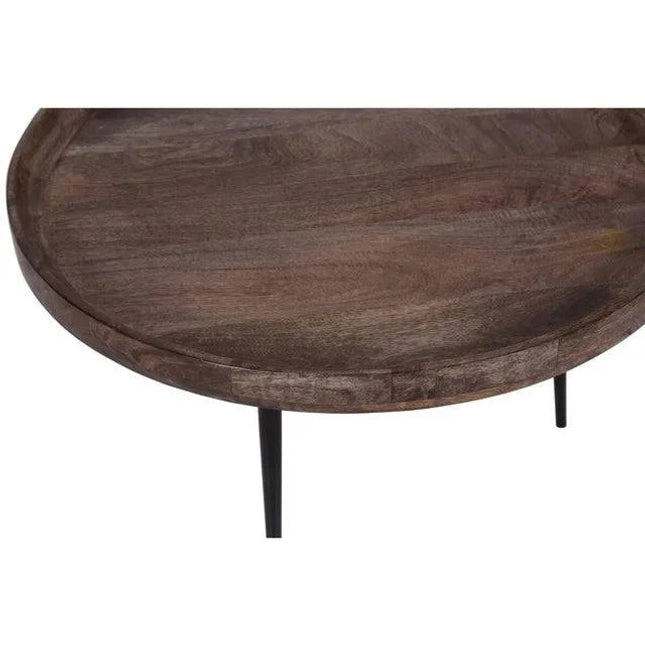 The Mango Bowl Coffee Table features a polished, dark mid-century style round wooden tabletop made from ethically sourced mango wood. It rests on three black metal legs and has a tray-like appearance with its slightly raised edge and visible wood grain for added texture.