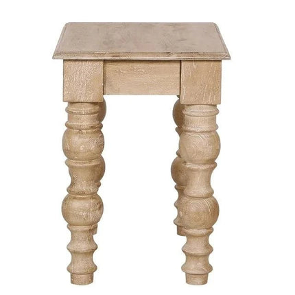 The French Country Side Table features a square wooden top and four intricately carved, turned legs in a distressed natural finish, offering rustic sturdiness and French-country-inspired charm.