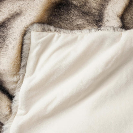 A close-up of the RCL Fur Throw reveals a smooth cream side and a faux fur side with grey and brown tones, offering inviting textures that radiate comfort and warmth.