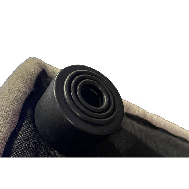 Close-up of a black cylindrical rubber Feet stopper on the edge of a textured gray-black fabric object, featuring a spiral pattern on top and surrounded by padded material.