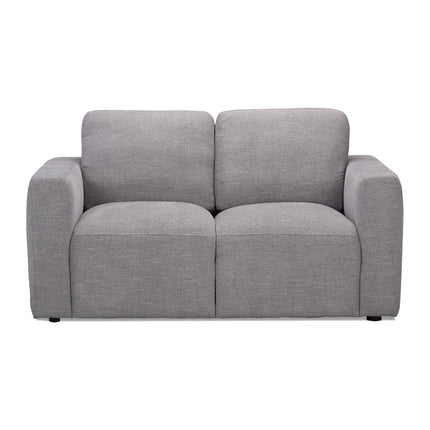 The Lugano Loveseat, crafted with premium materials, boasts a gray, two-seater design with wide armrests and smooth upholstery. Its modern elegance and plush cushions bring an inviting aura of Italian luxury to any space.