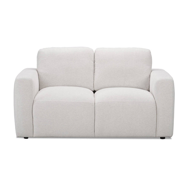 The Lugano Loveseat captures Italian luxury with a minimalist, plush design. This modern white two-seater boasts thick, rounded arms and cushioned backrests. Crafted from premium materials, the fabric is soft and smooth on a plain white backdrop, exuding cozy elegance.