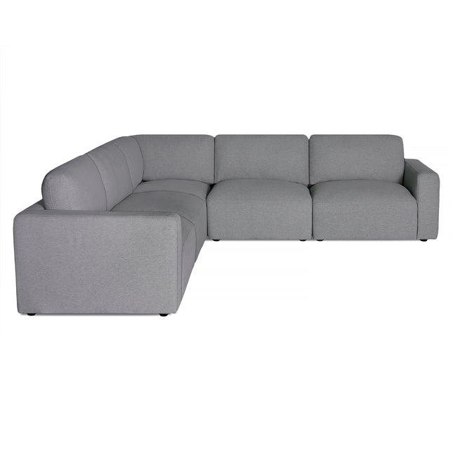 The Free Fabric Swatches offer a minimalist modern design with an L-shaped light gray sectional featuring clean lines, a low backrest, and thick cushioned seats. It is supported by discreet black legs for a sleek, contemporary appearance.
