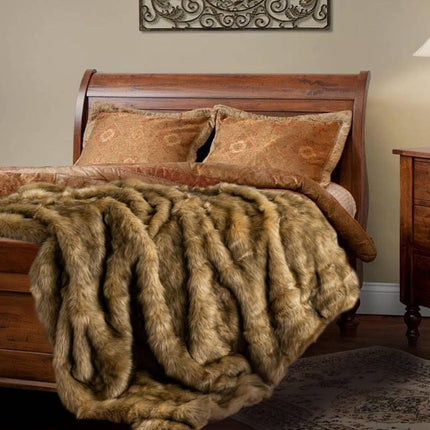 A wooden sleigh bed features ornate pillows and a brown patterned duvet, with the RCL Fur Throw draped over the foot. A wooden nightstand holds a lamp, while decorative art adorns the wall above.