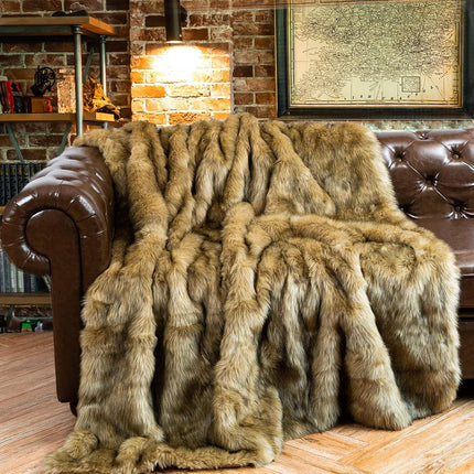 An RCL Fur Throw in shades of brown adorns a brown leather sofa. The cozy setting features a brick wall, a lit lamp, and a wall map, establishing a warm, rustic ambiance.