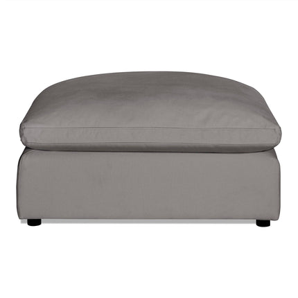 The Peyton Ottoman is a sleek gray rectangular piece with a large cushioned top, showcasing modern design with plush comfort, set stylishly against a white background.
