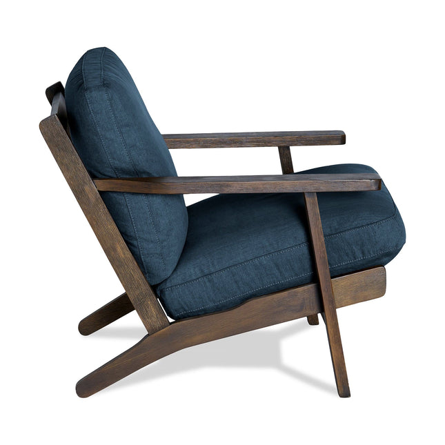 The Peyton Chair showcases a stylish mid-century modern design with a dark wooden frame and deep blue upholstery. It features angled legs and a slightly reclined backrest, blending retro aesthetics with comfort for any living space.