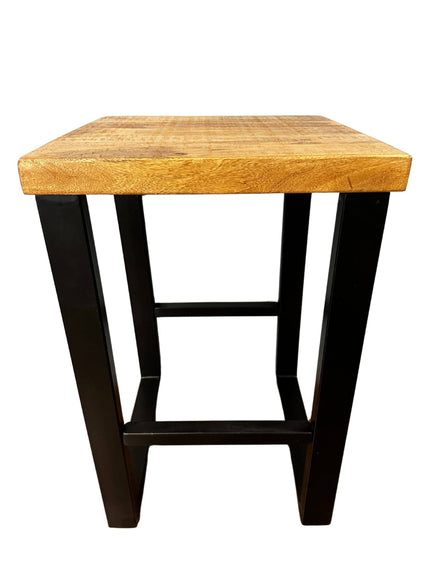 The Mango Stool is a small, square accent piece crafted from sustainable mango wood with black metal legs. Its minimalist design features a simple crossbar for support, and the natural wood finish beautifully complements its sleek modern aesthetic.