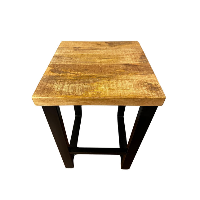 The Mango Stool, made from sustainable mango wood, features a square top and elegant black metal legs. Its natural finish reveals beautiful grain patterns when viewed from above, making it an ideal accent piece for any room.