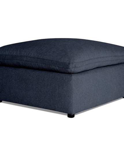 A dark gray My Cloud 40 Ottoman, with a large cushioned top and low-profile legs, sits elegantly on a plain white background, showcasing the art of comfort and customizable options.