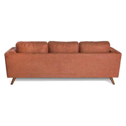 A rear view of the Maddox Sofa shows its orange hue, mid-century modern style, three plush back cushions, and angled wooden legs.