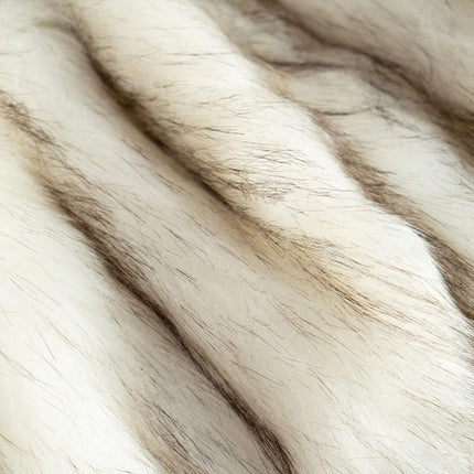 Close-up of the RCL Fur Throws soft, cream-colored faux fur features long, fine brown strands. Its plush texture resembles a luxurious faux-fur blanket, with visible light and shade variations enhancing its natural feel.